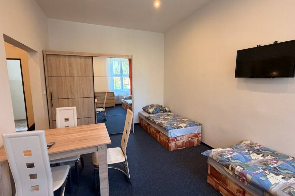 Apartmán č. 2 — obytná část se třemi lůžky, stolem a televizí